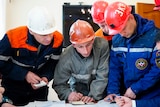 Rescue workers in hard hats prepare to go into a mine.