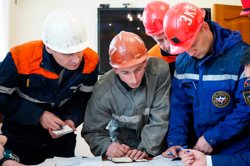 Rescue workers in hard hats prepare to go into a mine.