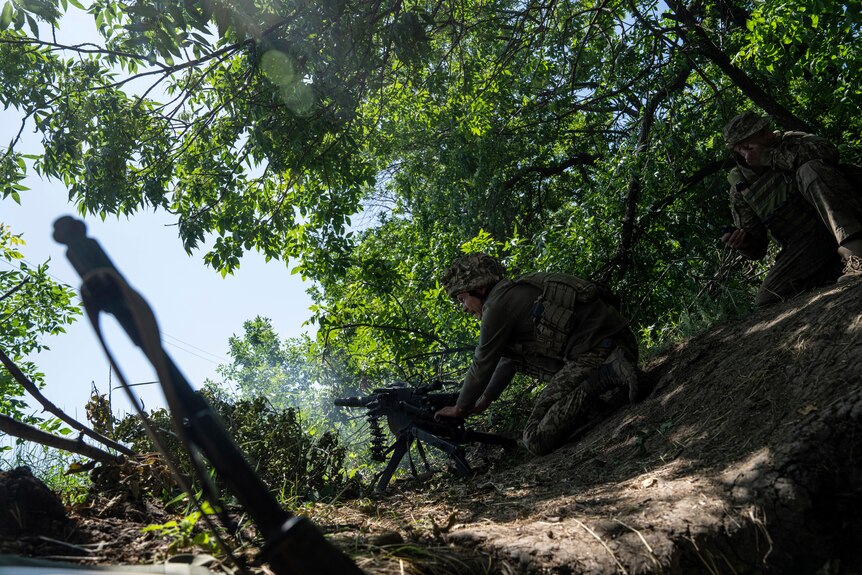 A low angle of a man holding a gun in a forest. 