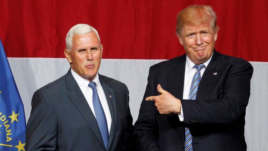 Donald Trump points at Mike Pence as the two stand on a stage together.