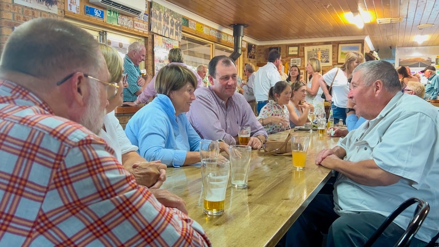 two women and three men sit around a table talking with beer glasses on the tables