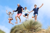 Prince William jumps into the air with his three children as they hold hands