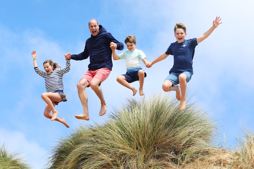 Prince William jumps into the air with his three children as they hold hands