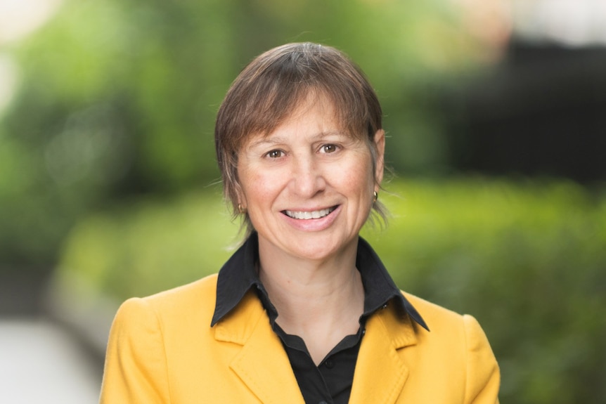 A woman in a yellow jacket smiles