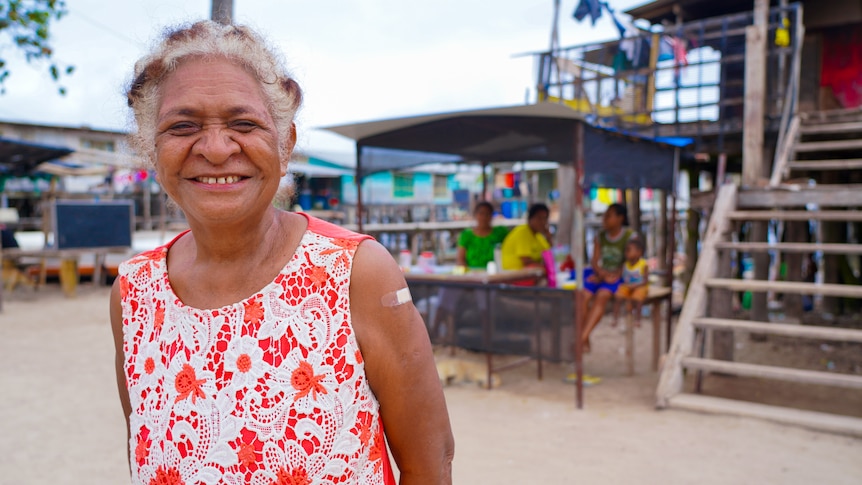 A Papua New Guinean woman with a band-aid on her shoulder grins for the camera