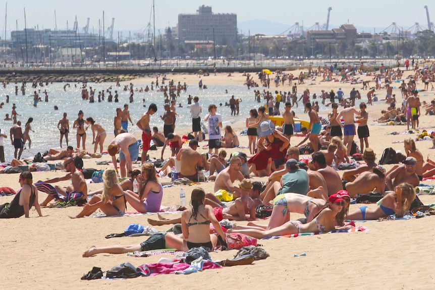 A large crowd of people gathers on St Kilda Beach.