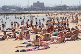 A large crowd of people gathers on St Kilda Beach.