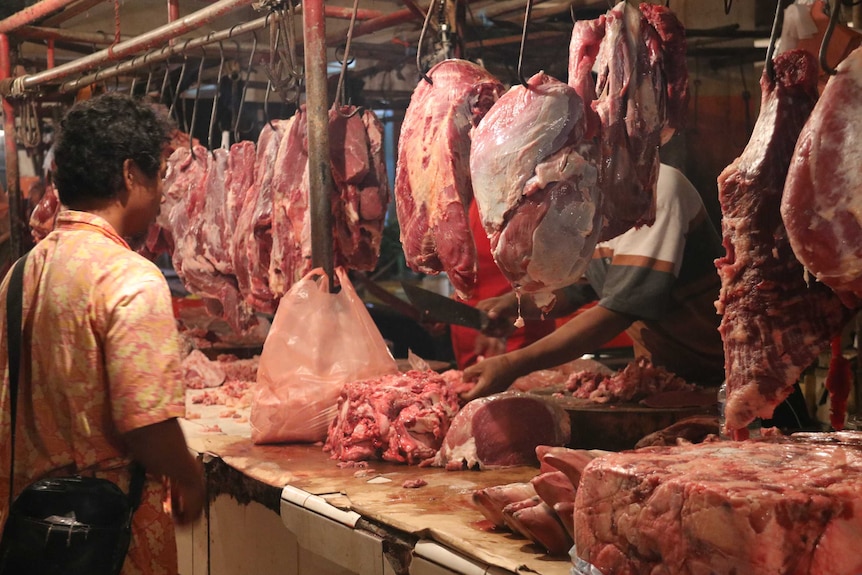 A customer watches on as the butcher prepared the beef at an Indonesian wet market.