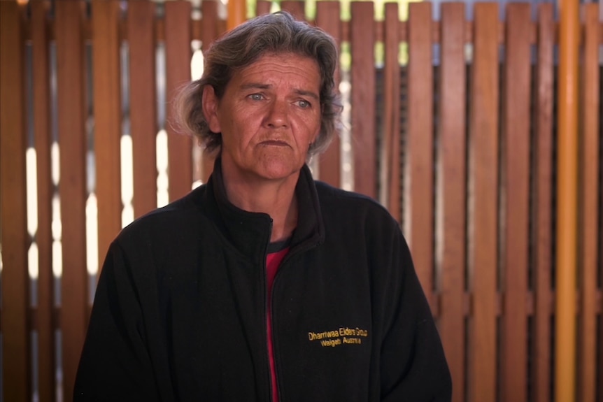 A middle-aged Indigenous woman with short grey hair and a distressed expression on her face.