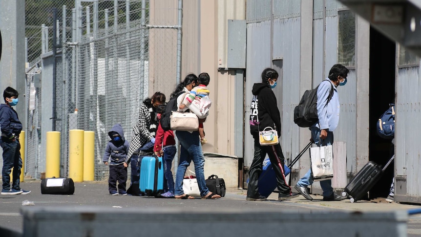 Air travellers enter a building at an airport while wearing masks.