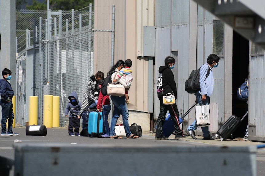 Air travellers enter a building at an airport while wearing masks.