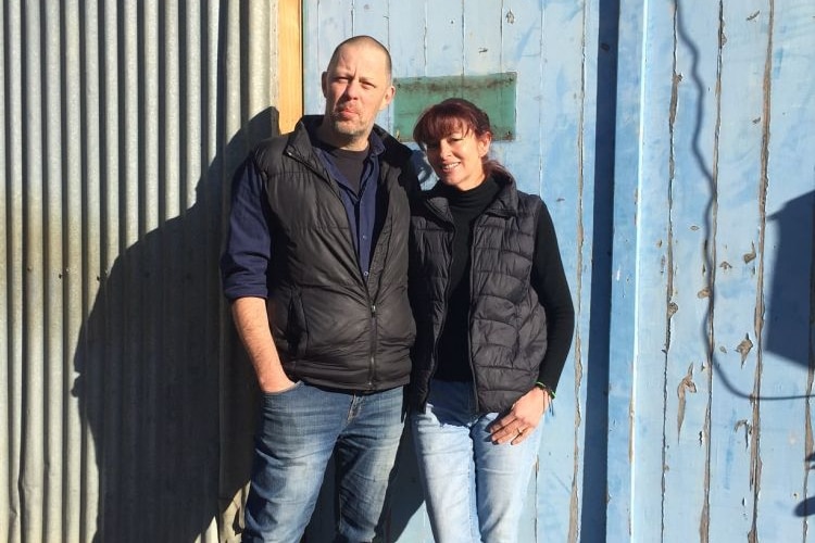 Trevor Memory and his wife Gemma standing in front of the galvanised and rustic timber renovated apple shed at Gardners Bay.