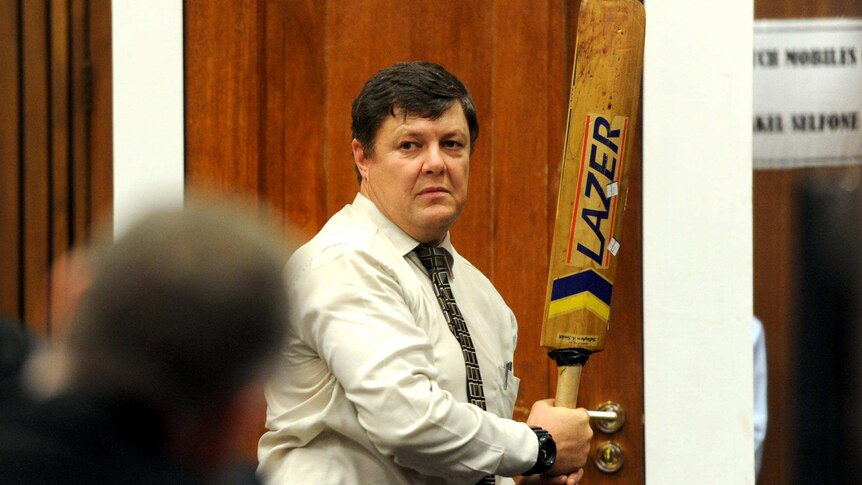 Colonel Johannes Vermeulen holds a cricket bat during cross-examination at the Oscar Pistorius trial.