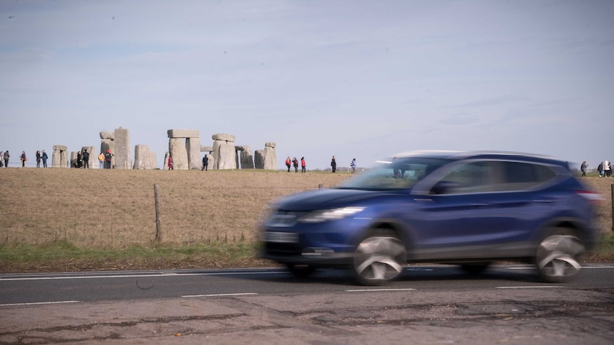A four-wheel-drive passes by the Stonehenge site on the A303 road.