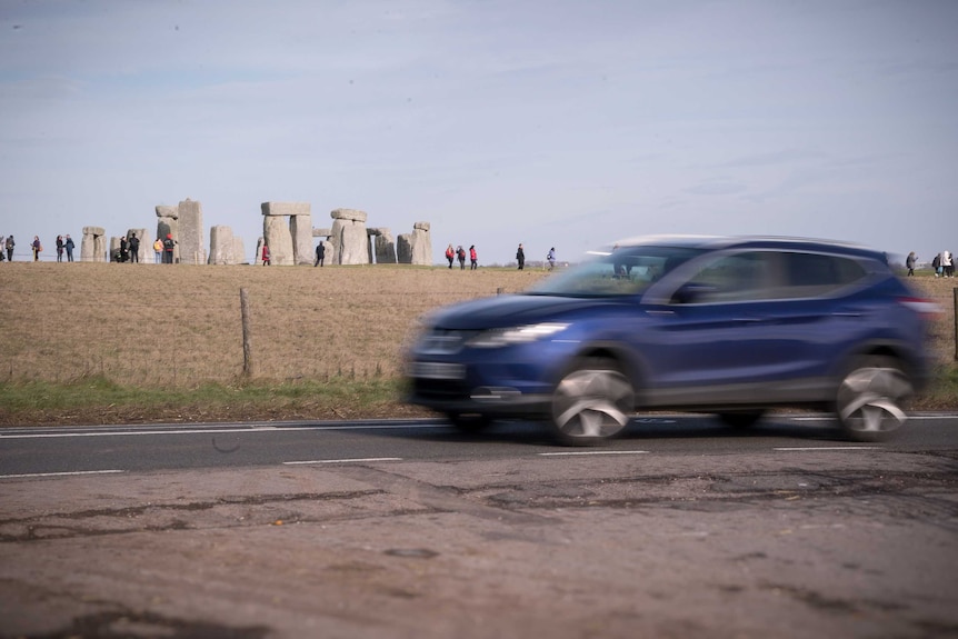 A four-wheel-drive passes by the Stonehenge site on the A303 road.