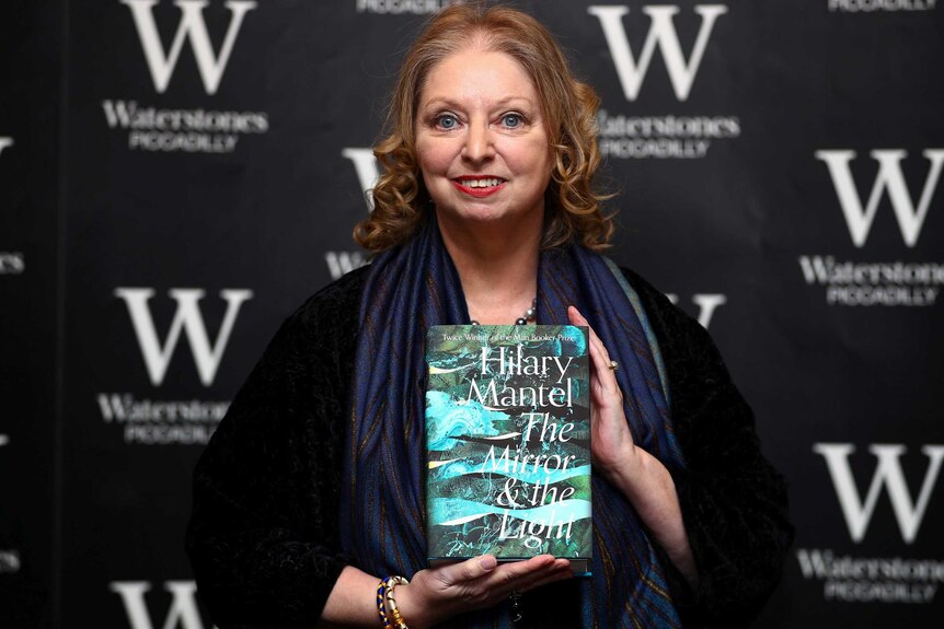 Hilary Mantel holds up her book as she attends a book signing for her novel The Mirror and the Light.