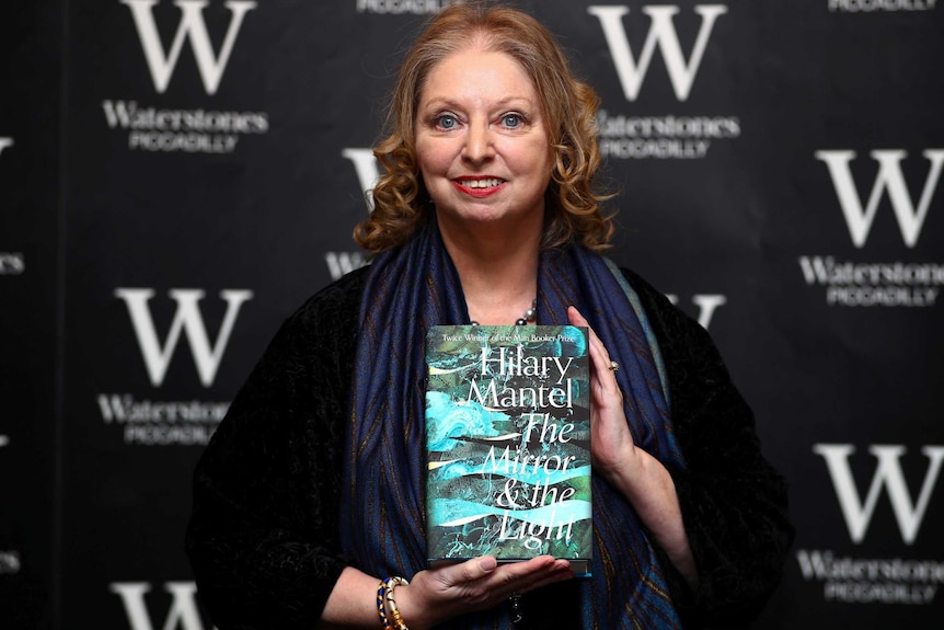 Hilary Mantel holds up her book as she attends a book signing for her novel The Mirror and the Light.