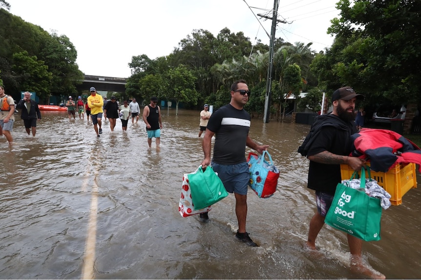 Several people carry belongings through water
