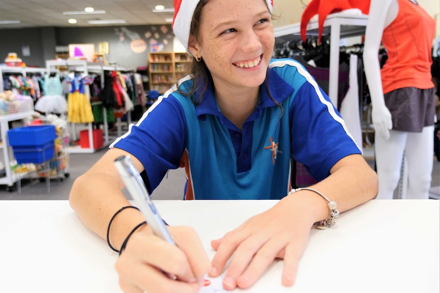 Madelaine McDonald writing her giving tree gift tag for the ABC Radio Darwin St Vincent de Paul appeal