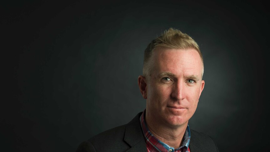 Dr Stephen Whyte from QUT stands in front of a navy background