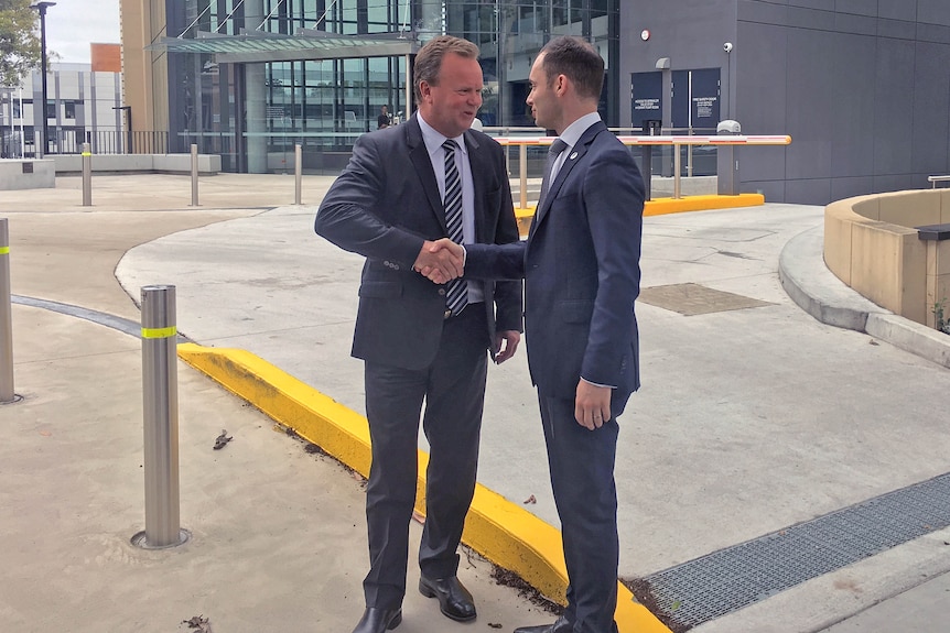 Rugby Australia CEO Bill Pulver shakes hands with RUPA chief Ross Xenos