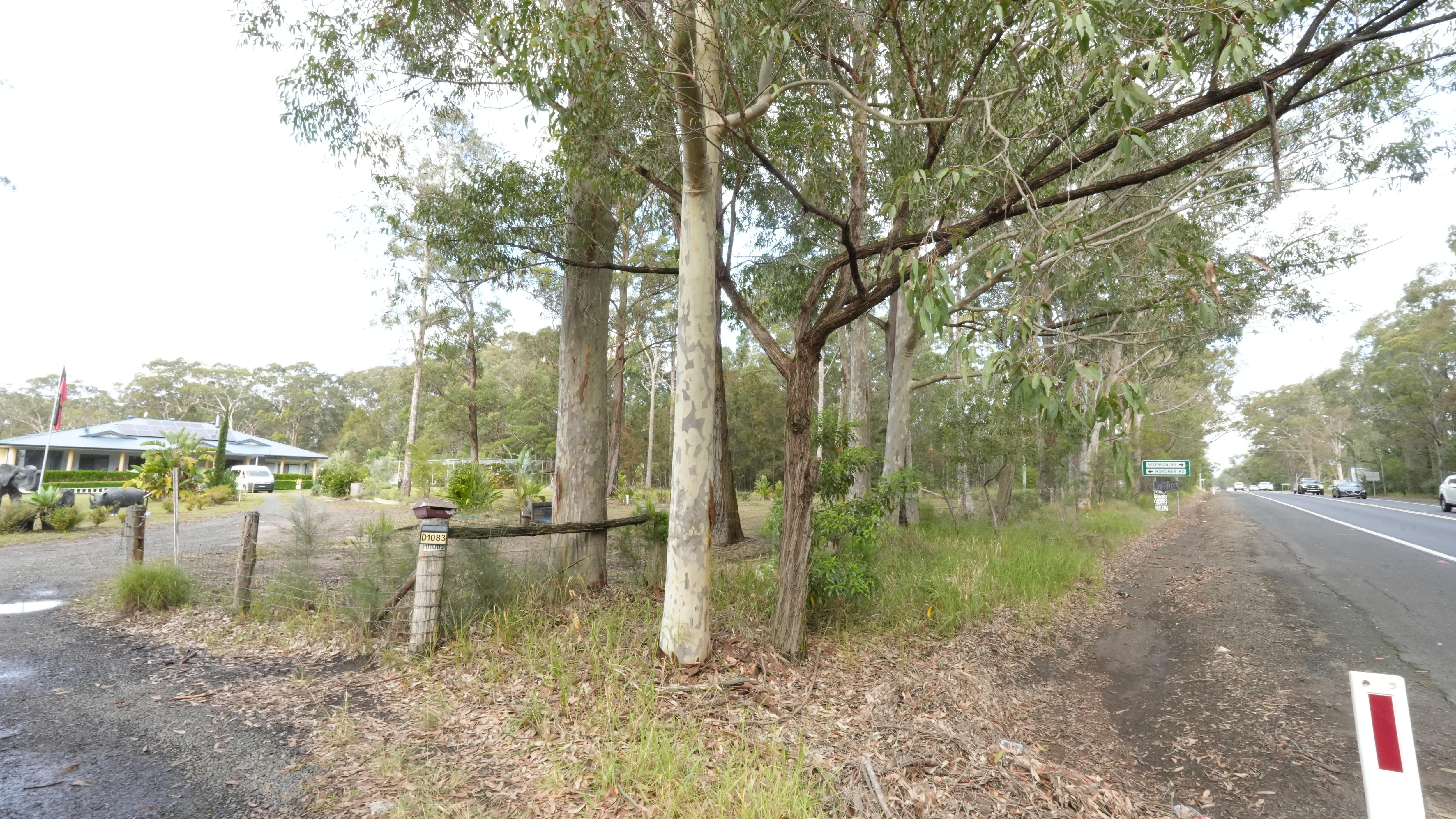 Wide shot of the home and the highway with trees in the middle.