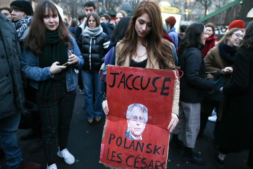 Female protestors hold a sign showing Roman Polanki's face with the words: J'accuse Polankski les Cesars