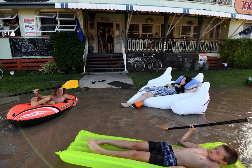 Pub worker Tahlia Thomasson (right) and local children play in floodwaters outside the Fitzroy Hotel