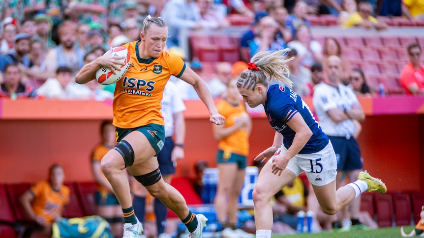 Australian sevens rugby player Maddison Levi running with the ball, down the wing, beating a diving defender