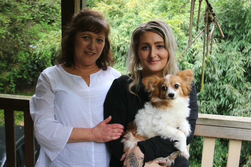 A mother and adult daughter, who is holding a terrier