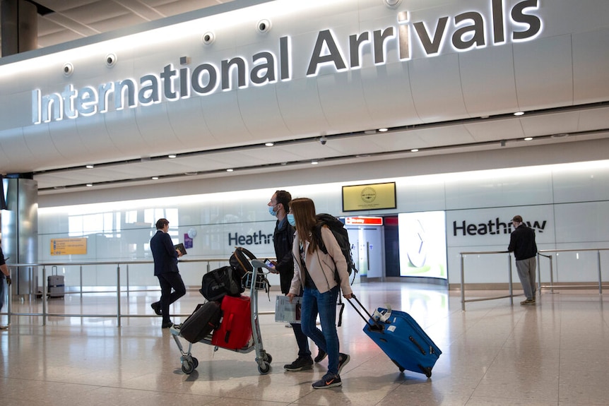 Two passengers wearing passengers wearing face masks arrive at London's Heathrow Airport.