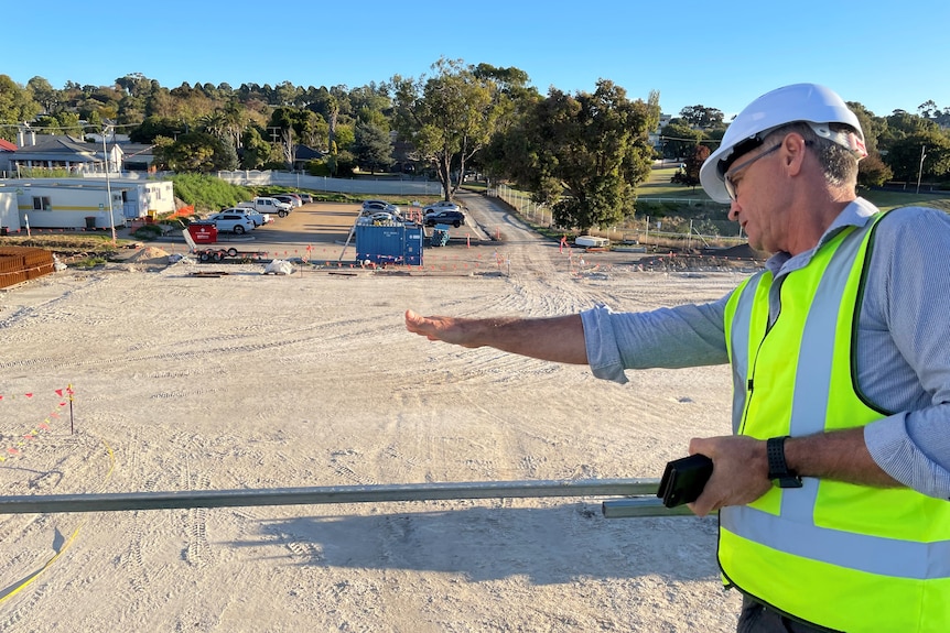 man points at area on construction site