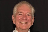 Man wearing dark suit and tie smiling at camera