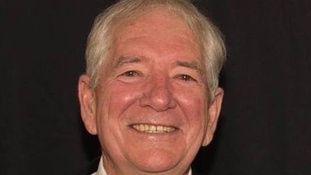 Man wearing dark suit and tie smiling at camera