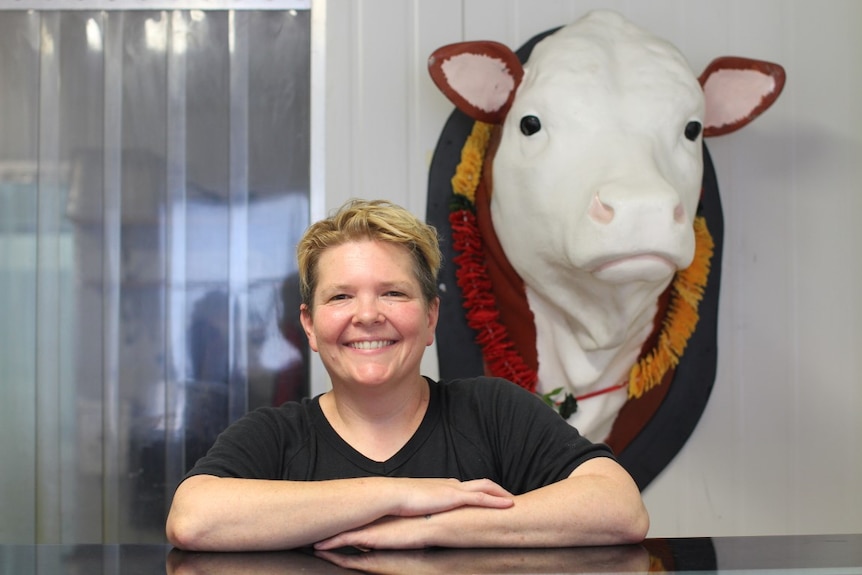 Businesswoman Susie Spoon is a vegetarian 'butcher'. Standing at her factory counter with a fake cow's head behind her.