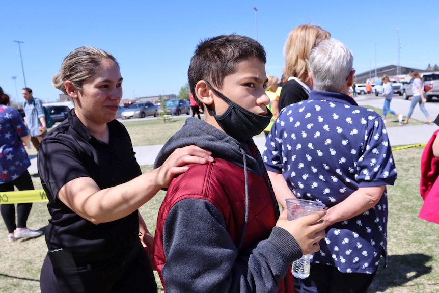 A woman puts her shoulder on her young son's shoulder.