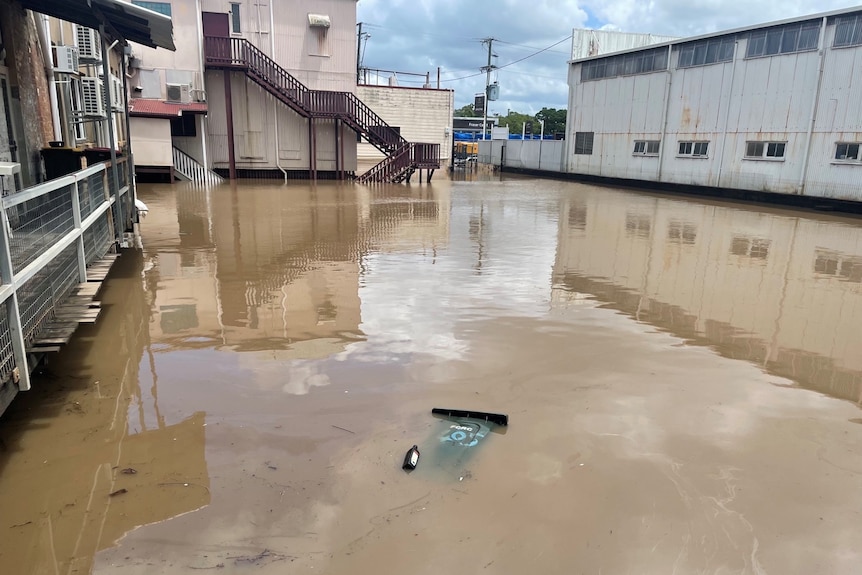 Brown flood waters reflect cloudy blue skies in the Maryborough central business district. 