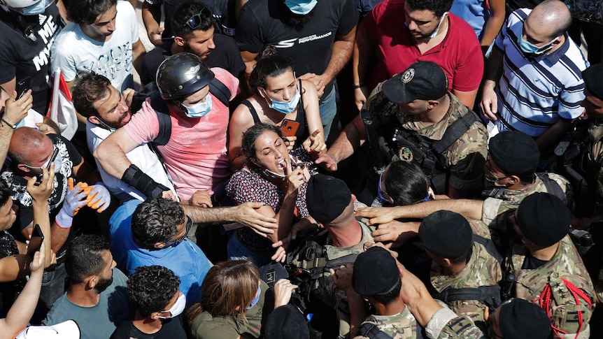 A woman yells at Lebanese soldiers as a sea of soldiers and people gather in the street.