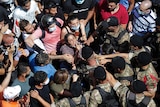 A woman yells at Lebanese soldiers as a sea of soldiers and people gather in the street.