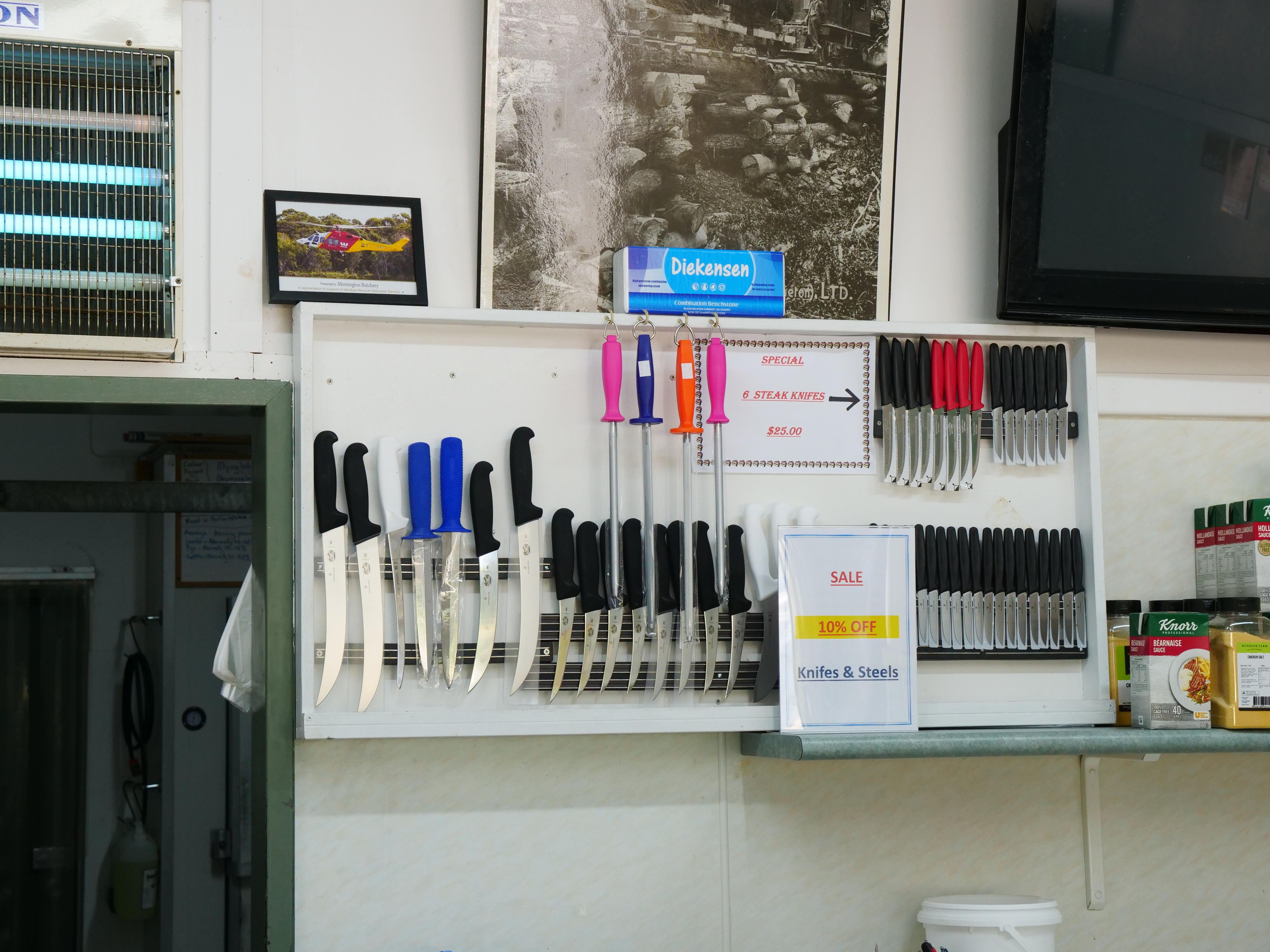 কসাইয়ের ছুরি এবং শার্পনারগুলি মর্নিংটন বুচারির ভিতরে একটি দেয়ালে ঝুলানো ছিল।