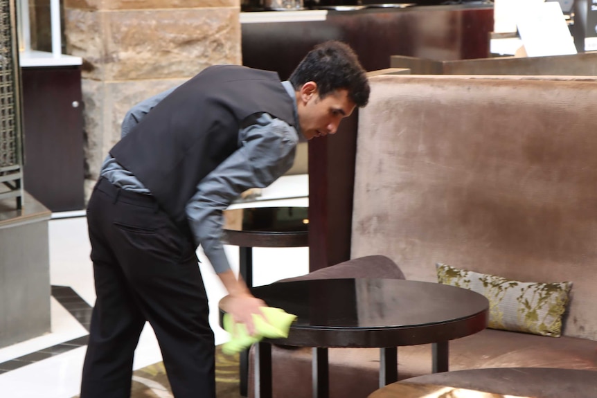 A worker cleans a table at a hotel.