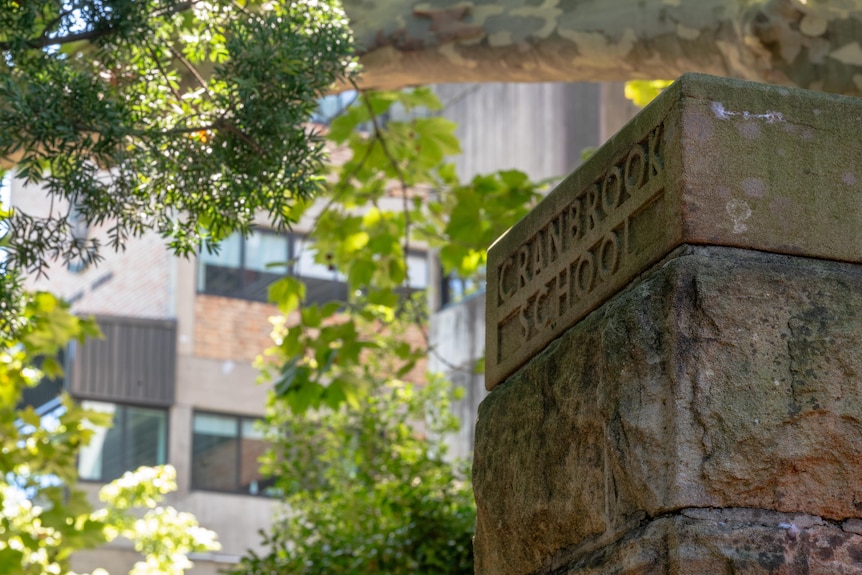 A sandstone column outside a school. The words 'Cranbrook School' have been carved out of the top stone.
