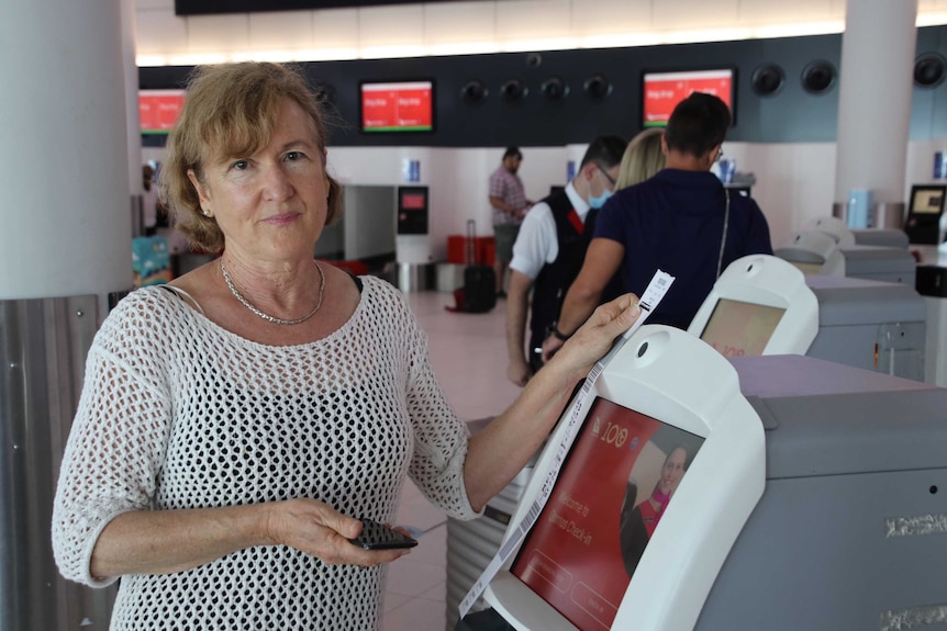 A woman stands next to an automatic check-in counter at Perth Airport.