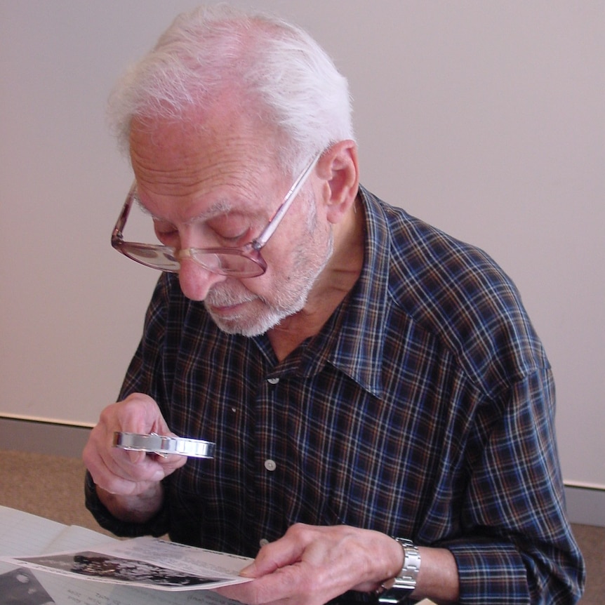 Dr Solomon Bard looking at old documents through magnifying glass.