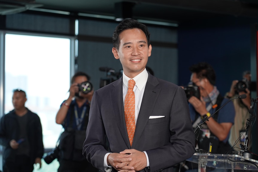 A young Thai man in a suit with his hands clasped before him