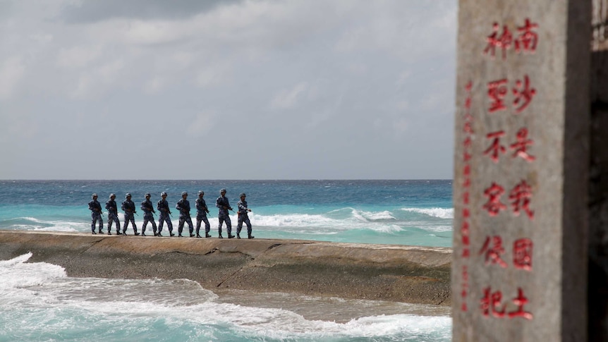Chinese soldiers patrol in the Spratly Islands, near a sign saying the land is "sacred and inviolable".