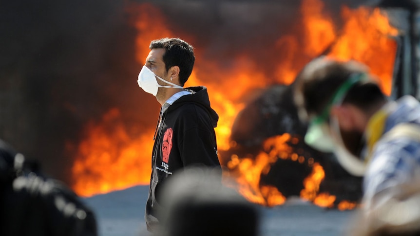 Protesters stand in front of a burning vehicle in Istanbul's Taksim Square.