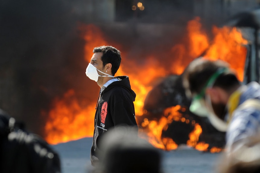 Protesters stand in front of a burning vehicle in Istanbul's Taksim Square.