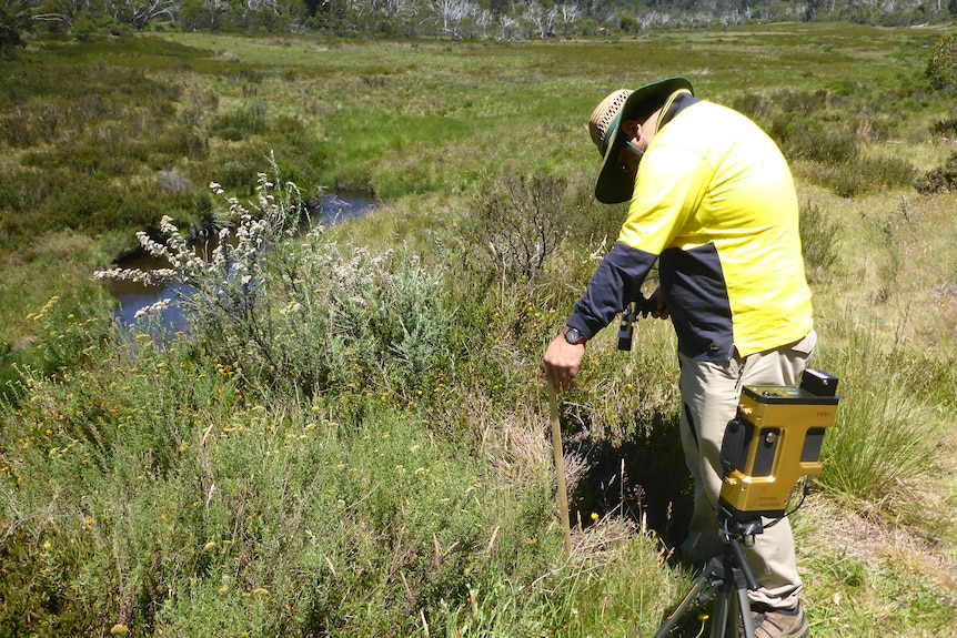 A man bent over some plants with a field spectroradiometer