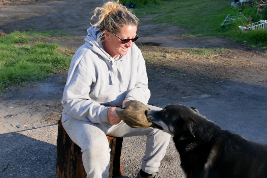 Woman smiles as she plays with her dog